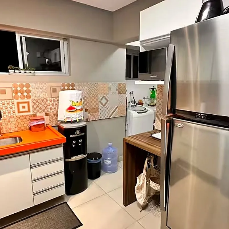 Cozinha com geladeira inox, bebedouro de galão e máquina de lavar