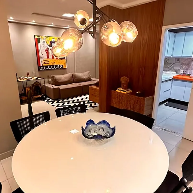 Mesa de jantar redonda em primeiro plano, sala e cozinha ao fundo