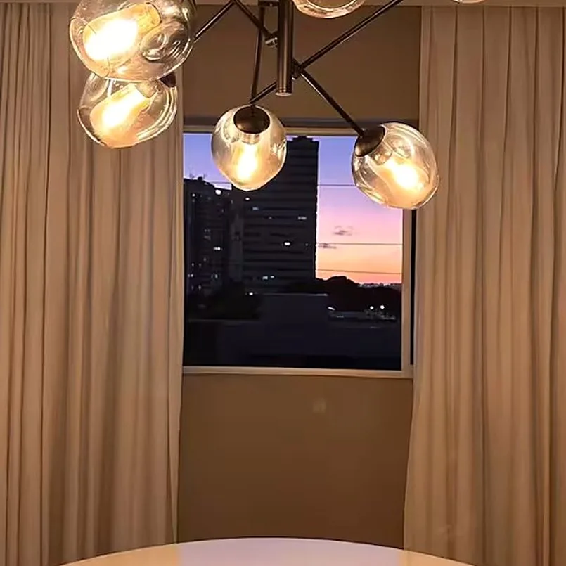 Pôr do sol pela janela da sala de jantar, com o lustre de vidro aceso